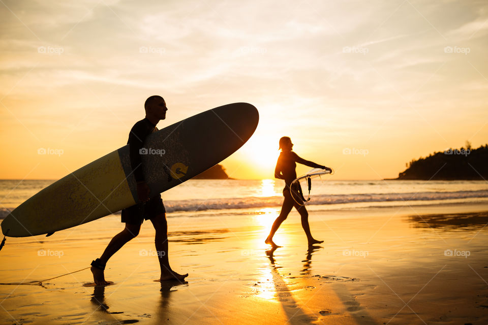 Silhouette of two surfers on the beach 