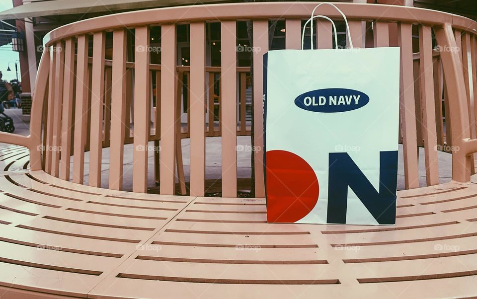 Old navy shopping bag propped on outside bench 