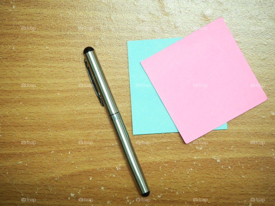 silver pen with paper note pink and blue on the wood table