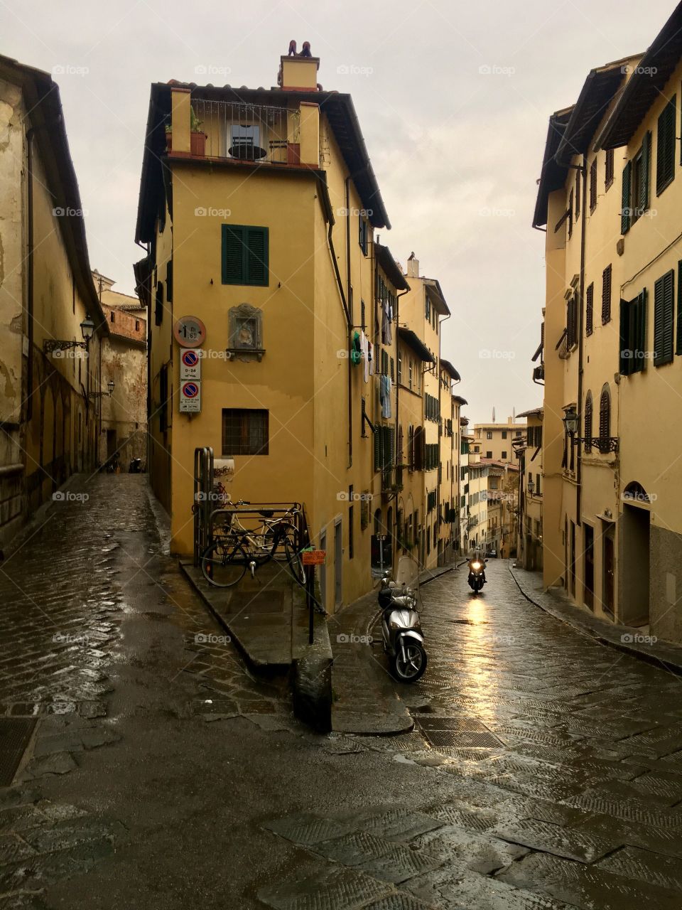 Lighted moped on a wet crossroads in Florence, Italy. 