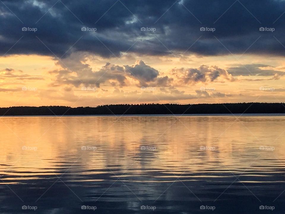 Scenic sunset view over the Baltic Sea archipelago with clouds reflection in the still rough water surface