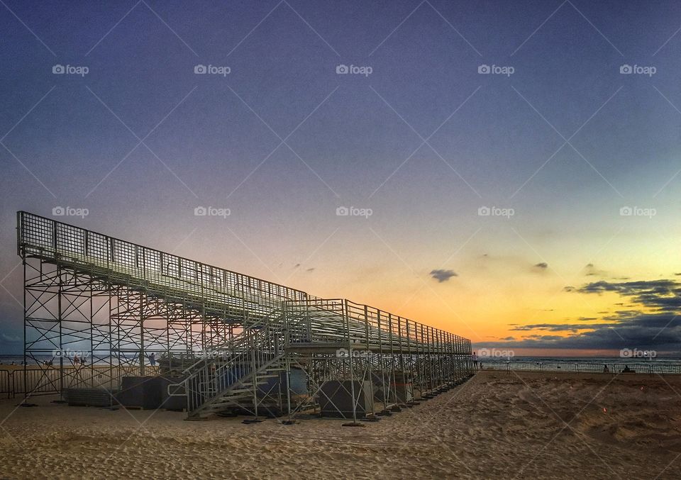 Metal bleachers on a beach silhouetted against the sky at sunset 