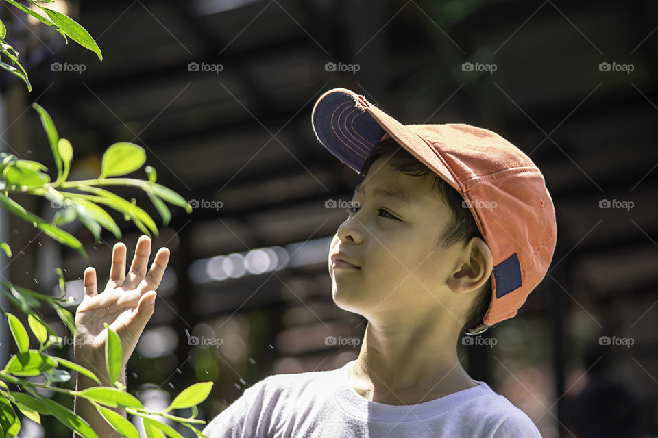 Portrait of Asian boy wearing a red cap and white  shirt is smile and Play water mist.