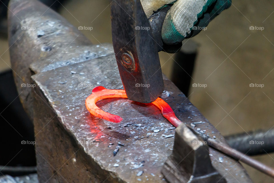 Blacksmith forges a horseshoe