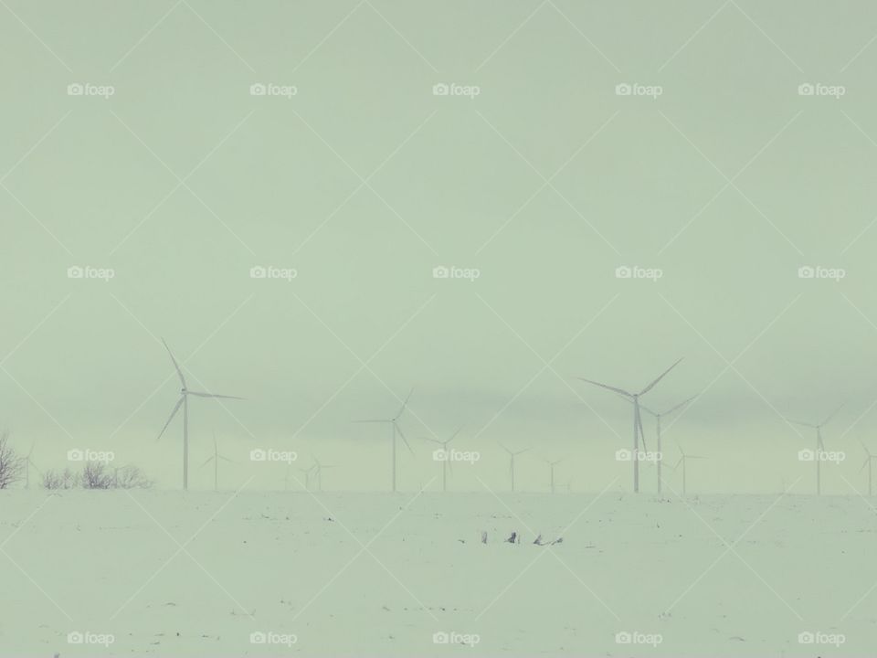 awesome use of wind energy/power in NW Missouri. cold windy snowy day, where the clouds and land blend together, the huge white windmills turning in Distance as far as the eye can see. these powerful windmills power several towns & outlying farms.