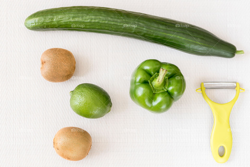 aerial view of green vegetables and fruit next to a  green peeler