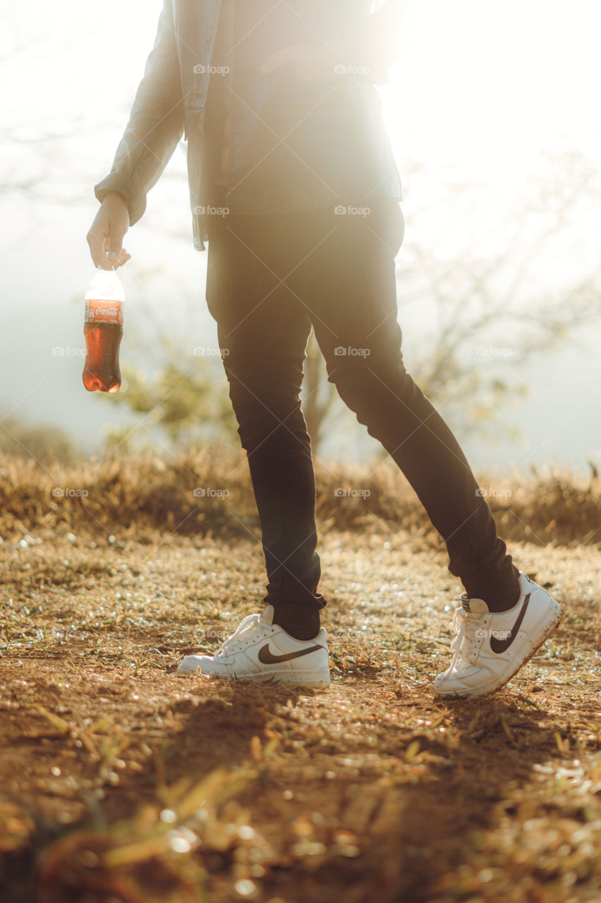 Boy walks with a delicious Coca Cola in a hot sunrise in the middle of the mountain