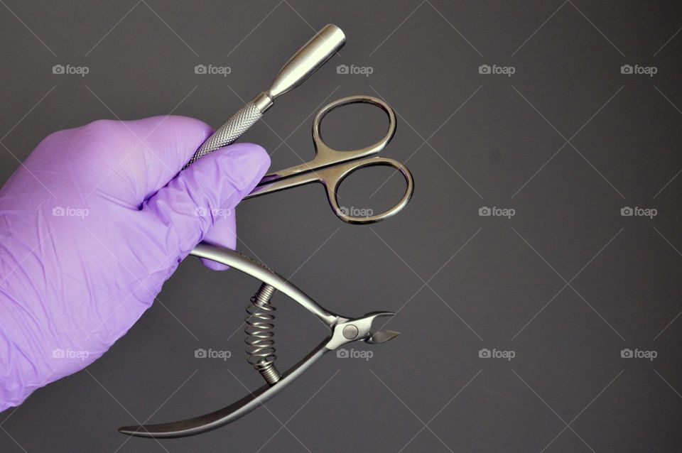 Manicure tools are held by a manicurist in rubber gloves