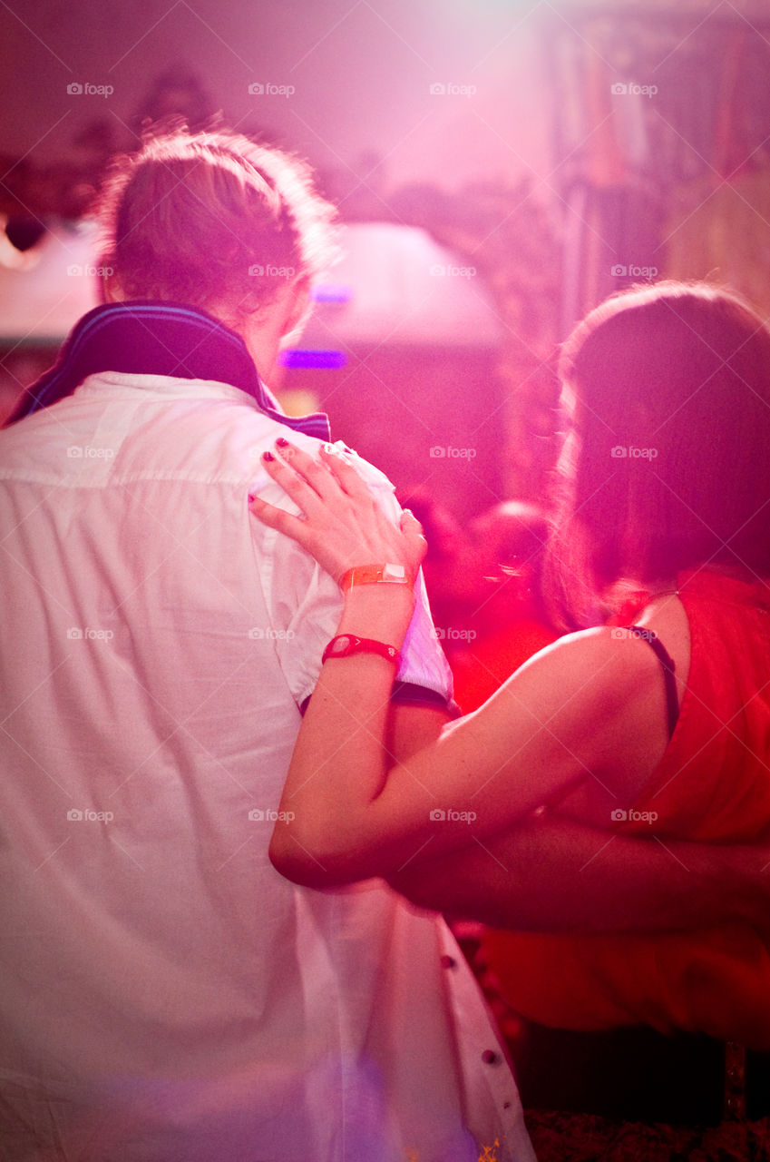 Photo taken from behind while two people dancing in purple light 