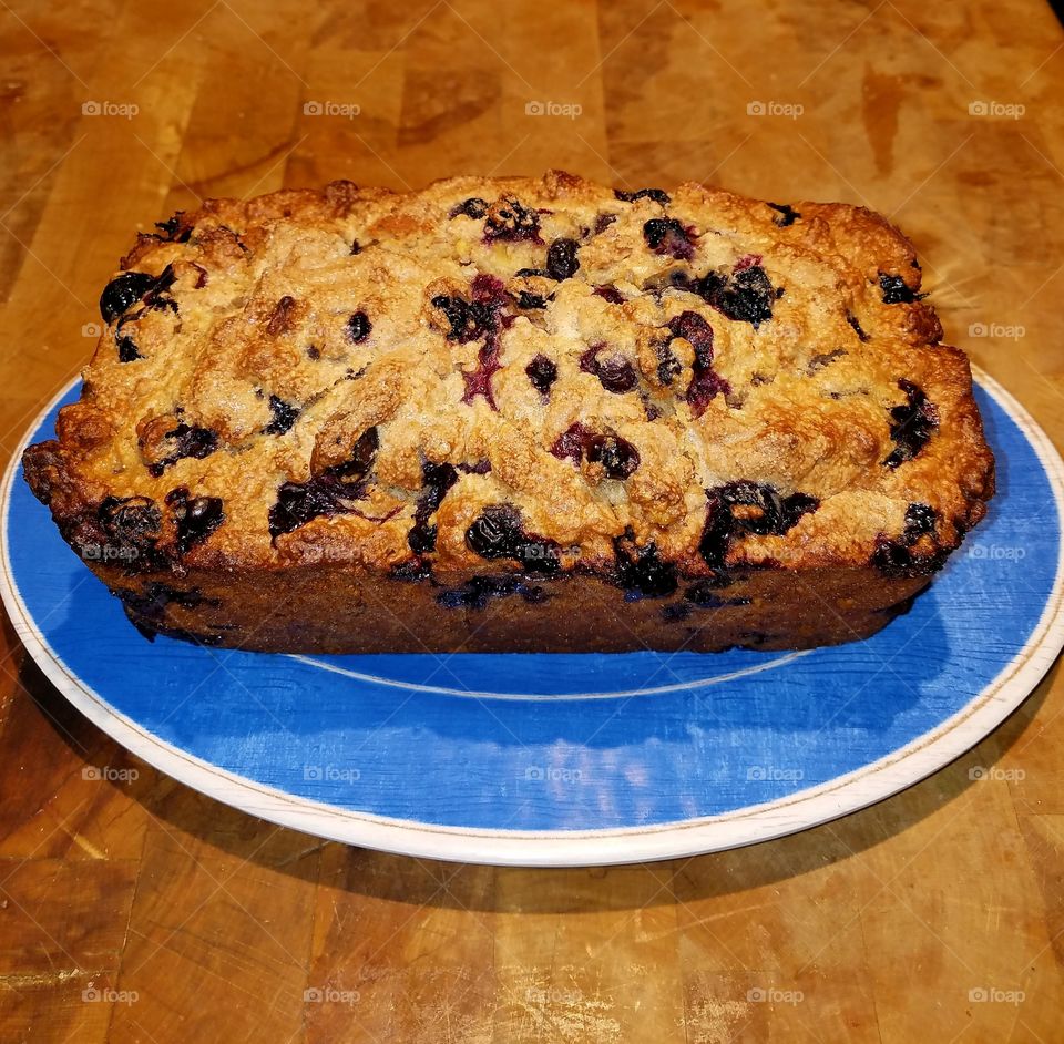 Blueberry Bread displayed on a blue plate, sitting on chopping block.