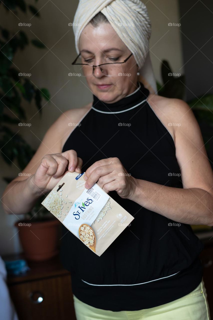 Aged woman with a cosmetics product in her hands, face mask brand St. Ives. Personal care