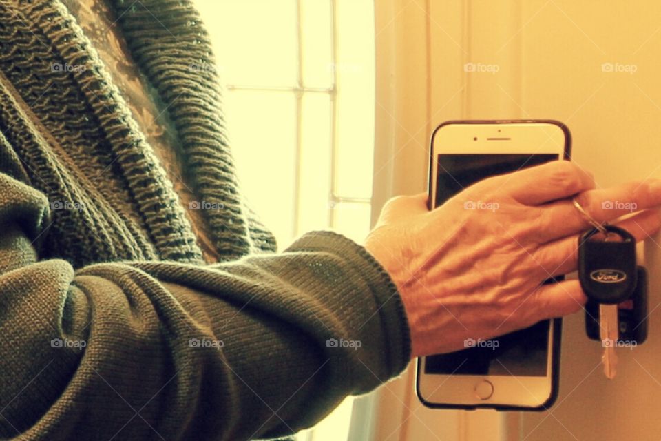 A woman dressed in s sweater leaving her house with phone and keys. 