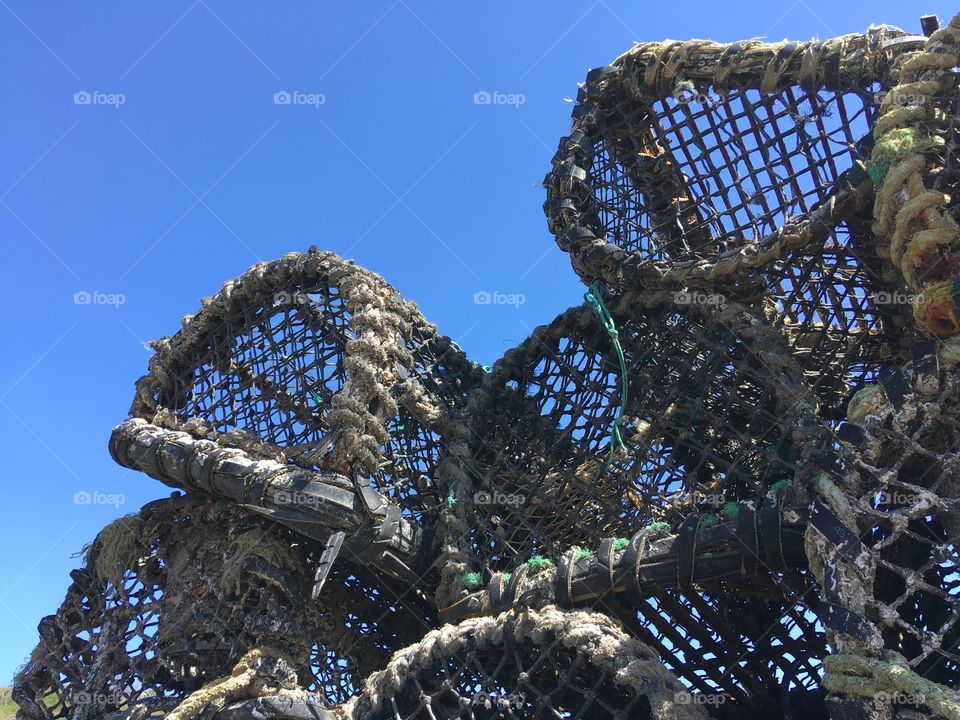 Lobster pots on the harbour wall with clear blue sky