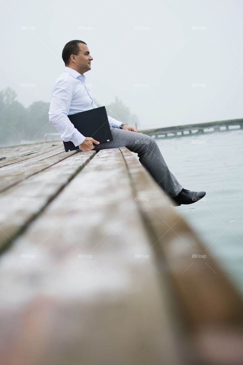 Business man with laptop on sea shore