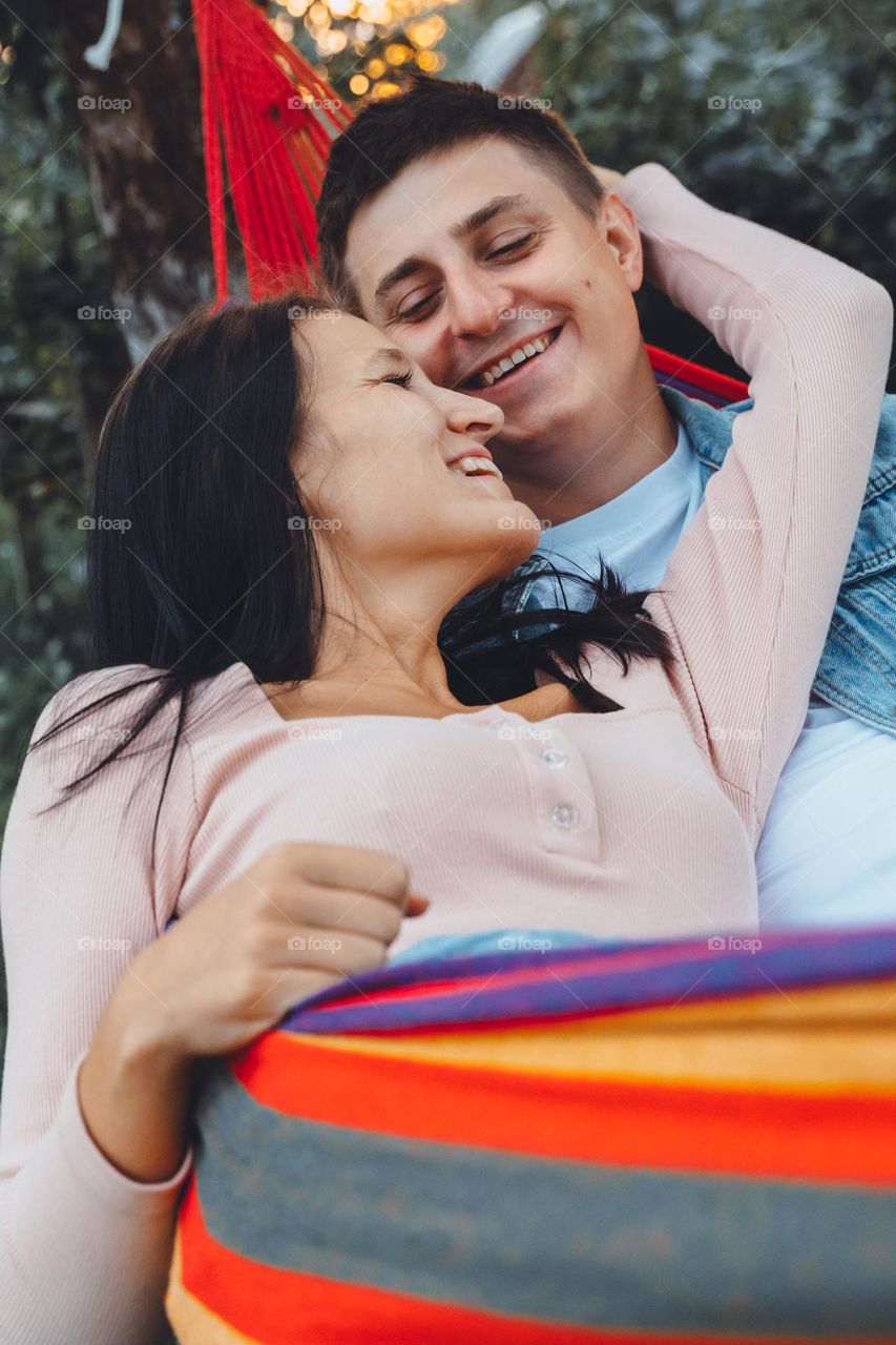 Happy couple in love relaxing in hammock hugging and kissing 