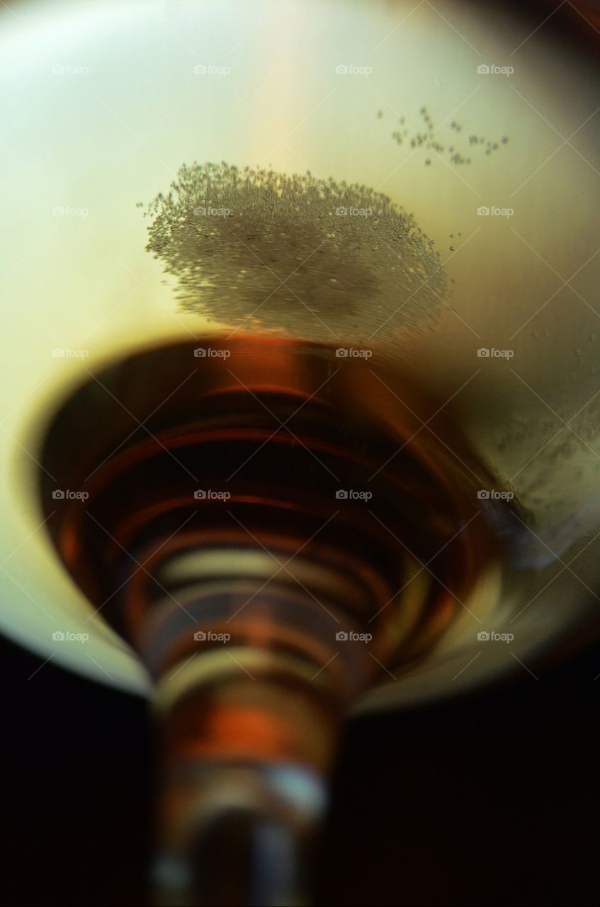 A glass of beer shot on a window seal is transformed into our planetary neighbor jupiter as sunlight reflects the lager creating a cosmic effect.