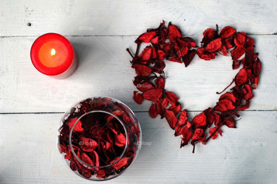 The figure in the form of hearts and flowers petals with a candle on a white background