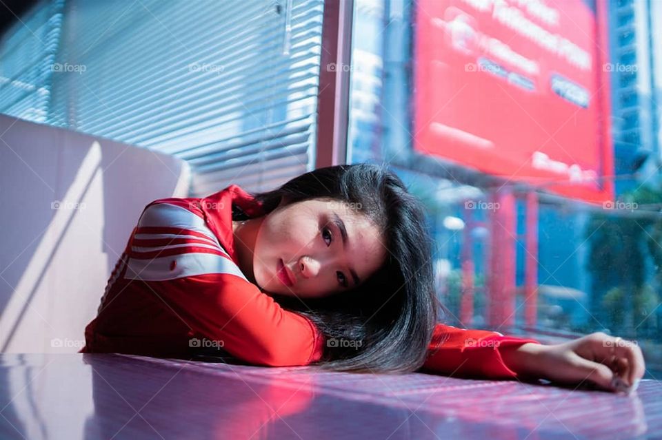 Korean girl with a red and white jacket. Relaxed on table.