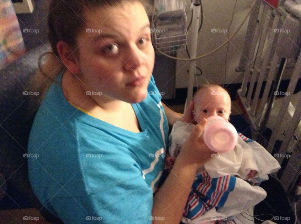 Older sister feeding sibling with Down syndrome after open heart surgery