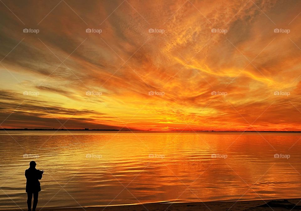Magic of the Sunset - A young lady photographs sunset. The radiance of the beautIful peach colored sky from the descending sunset was glorious to behold and increasing every moment in splendor. 