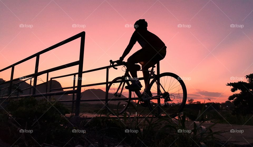 Black silhouette of men cycling in the evening.