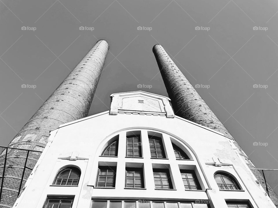 Black and white monochrome old fabric building facade facade with high tall narrow pipes bottom up