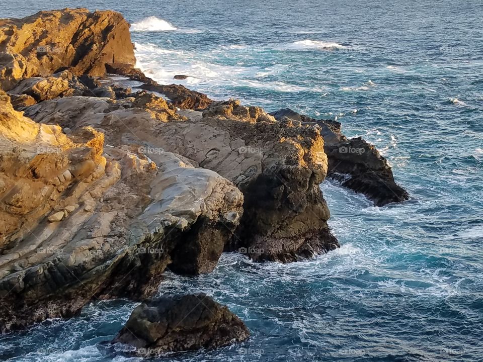Ocean waves surrounding craggy cliffs