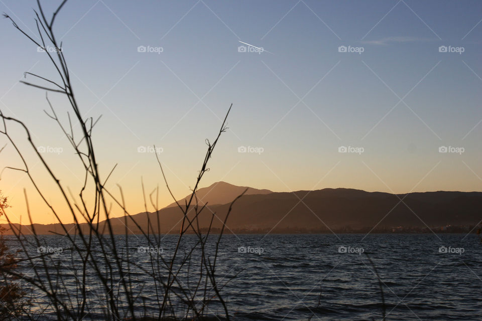 sunset with hills and sea, grass in foreground