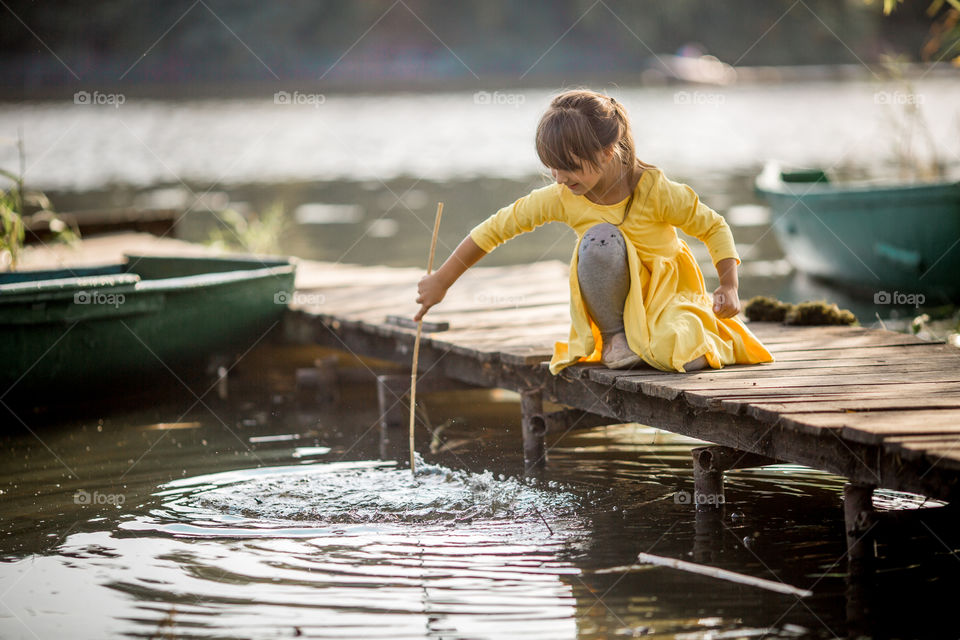 Little sisters playing near lake at autumn day 