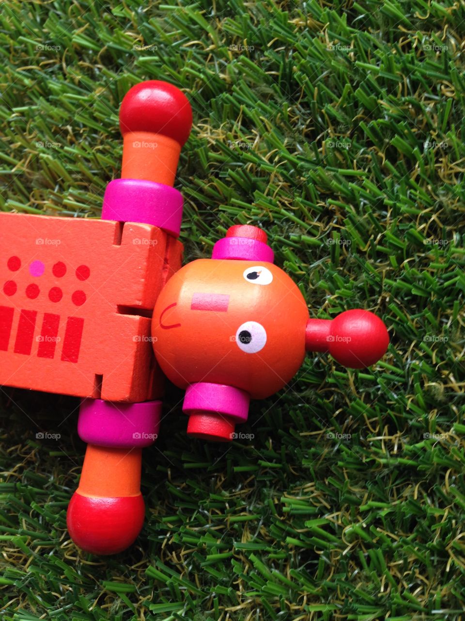 Red toy robot left on grass 