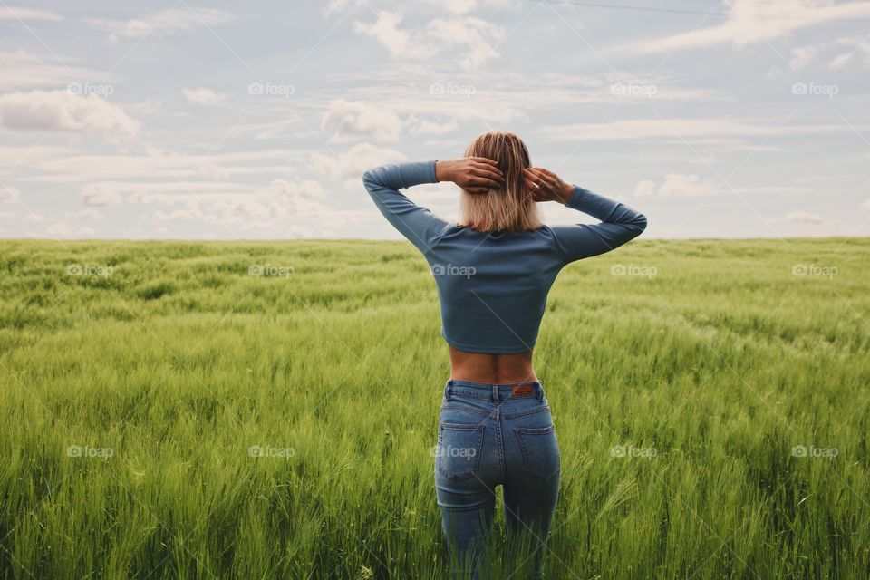 young woman stands with her back in the field