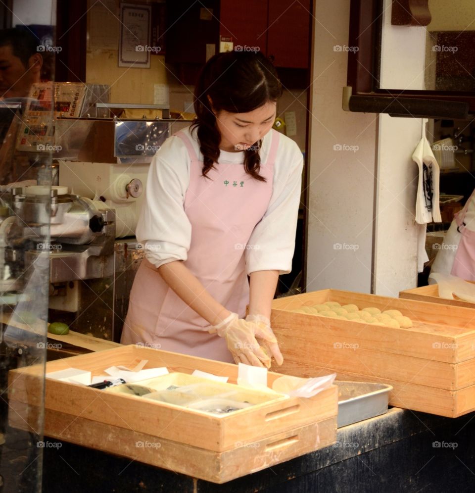 A young woman making typical Japanese pastries in a shop, in Japan 