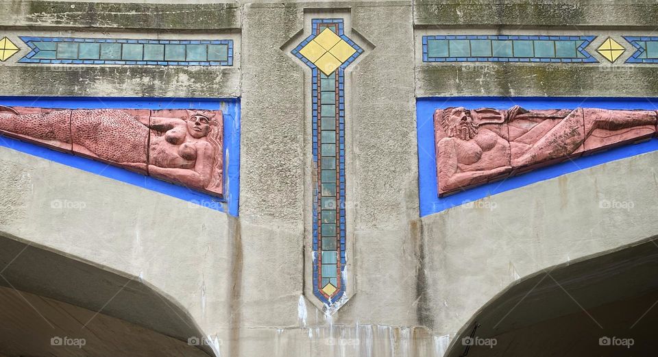 Neptune and a mermaid relief sculptures on the wall of an elevated train station in Brighton Beach, Brooklyn