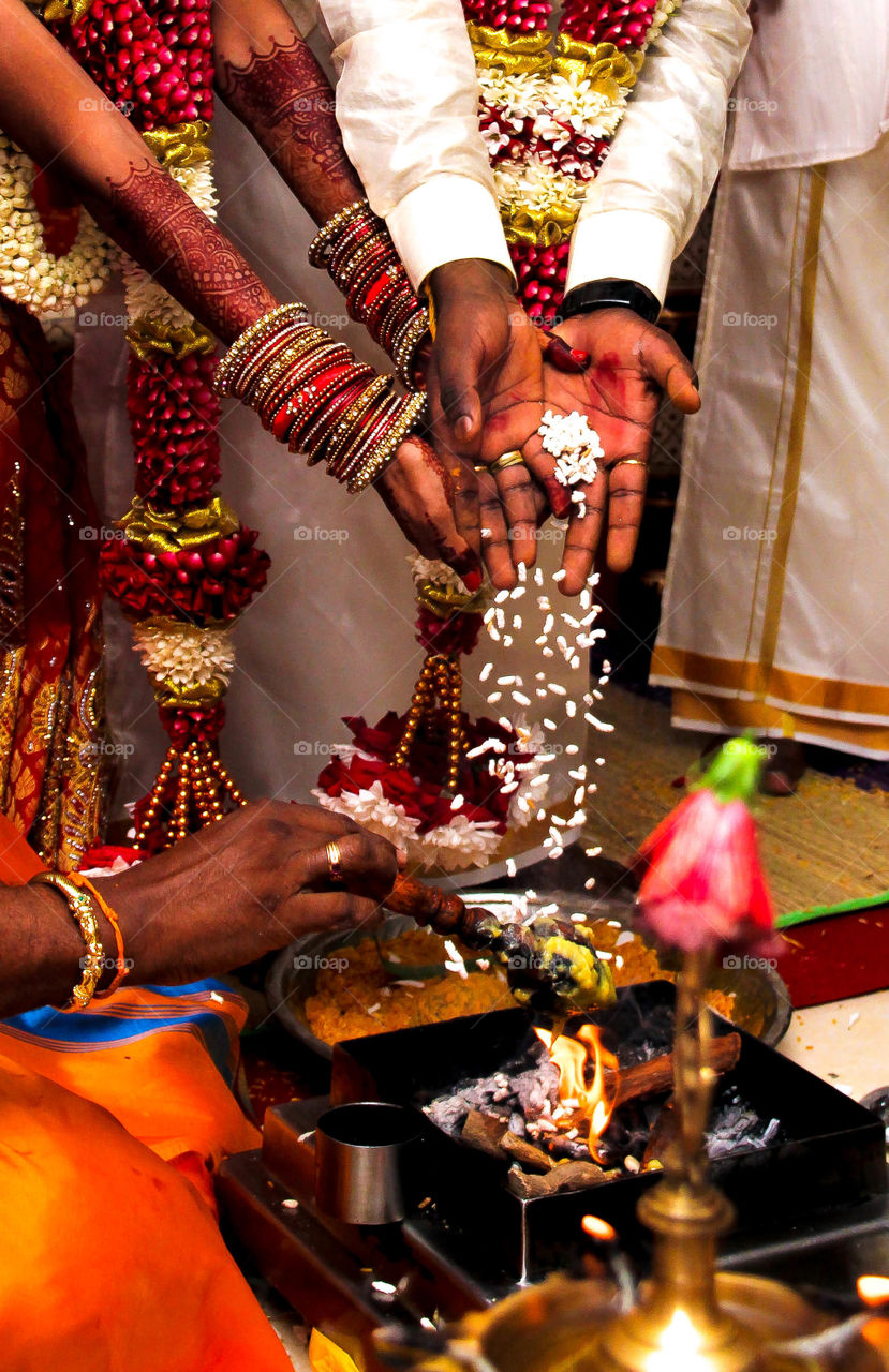 This is an Indian wedding ceremony of Divya, the bride and Selva, the bridegroom. They are finally married after 7 years of love. The wedding was held at Cameron Highlands Murugan Temple and was attended by many people. And to get married officially, the bride and bridegroom needs to take seven steps together around the sacred fire. This is one of the seven steps taken by the couple together around the sacred fire. A presence of the priest is very important in a wedding as they will conduct the wedding until the end of ceremony. The bride and bridegroom will have to walk around the sacred fire or more precisely circle the fire seven times with a garlands of flowers around each other’s neck with the priest chanting. By walking around the holy fire they are agreeing to these 7 steps. With each step, they throw small bits of rice into the fire after each blessing and finish one round. That act represents prosperity in their new life together. The fire plays an important role in a wedding especially in a Indian wedding. The fire or Agni represents the divine presence as a witness of the ceremony. Commitments/loyalty made in the presence of agni are made in the presence of God. 