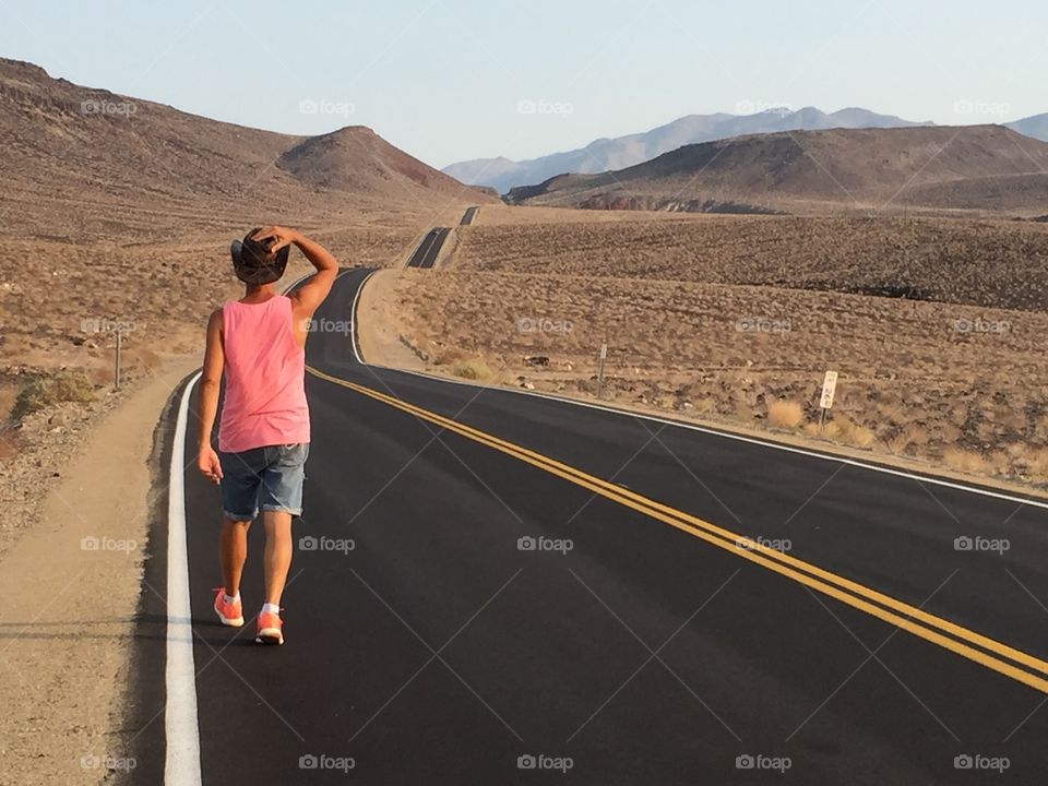 Man walks alone in a beautiful valley on a amazing road placed beside the Death valley