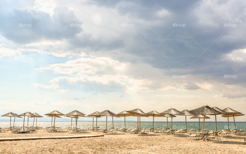 Straw Beach Umbrellas And Sunbeds On The Beach
