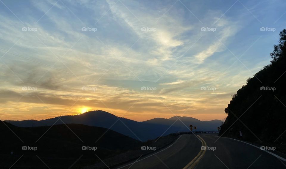 A sunset silhouettes distant as my hills in a mountain round