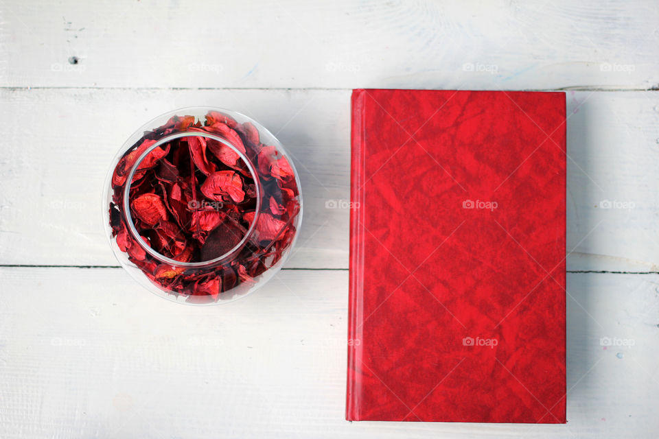 The book and the petals of dried flowers in a clear vase on a round white table