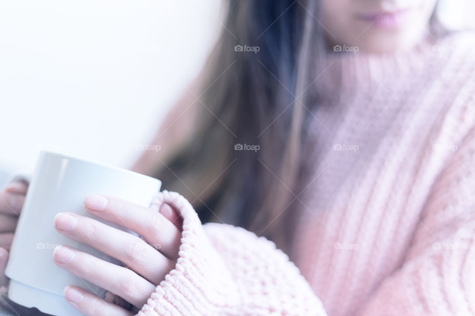 A woman wearing a cozy sweater and holding a cup