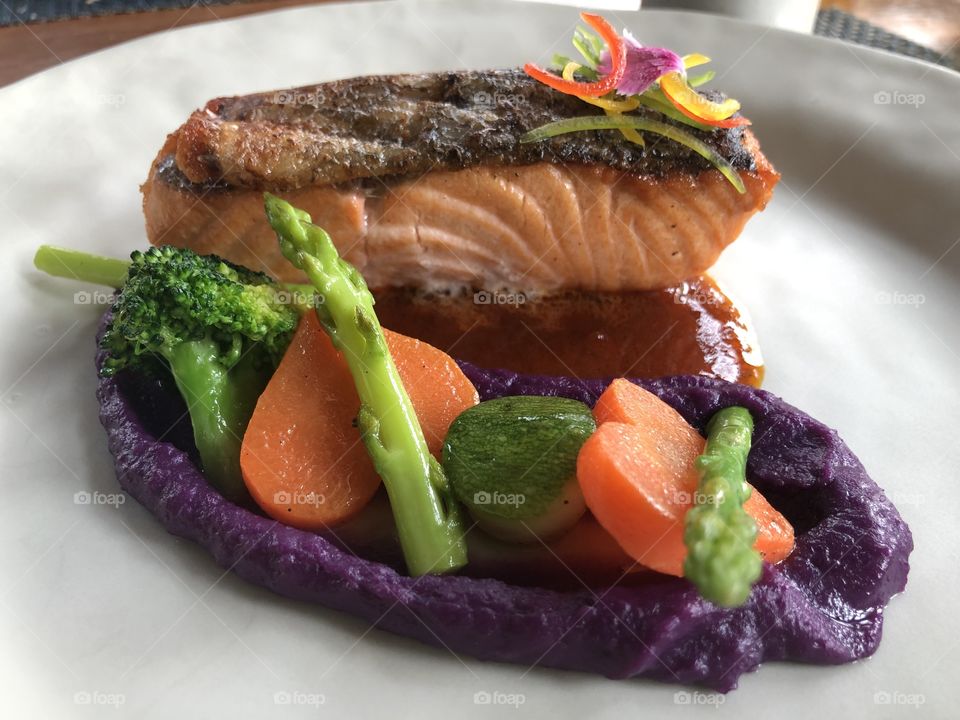 Salmon steak with carrots, asparagus and broccoli ,arranged and decorated beautifully and very appetizing in a white plate, the creativity of salmon steak served.