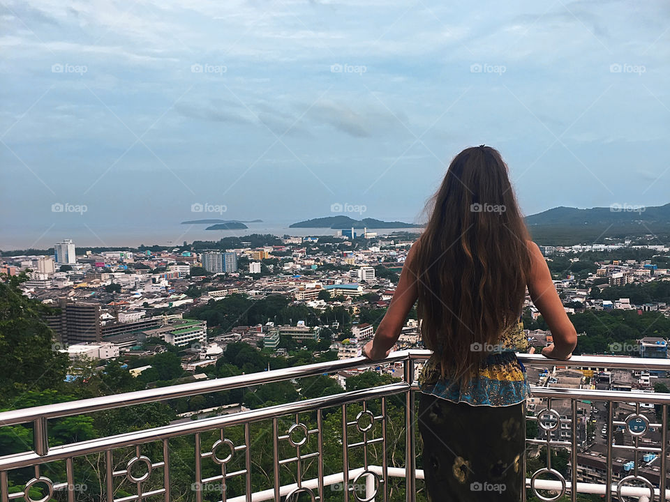 Young woman with long hair standing in front of beautiful evening city landscape in Thailand 