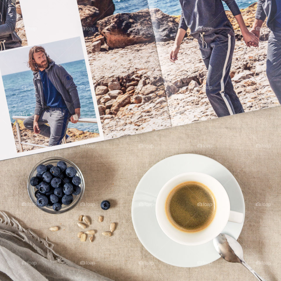 Morning coffee with a fashion magazine. Food photo, flat lay. Girl's breakfast: a cup of coffee on a textile napkin with a magazine, a saucer with blueberries and seeds. Healthy breakfast