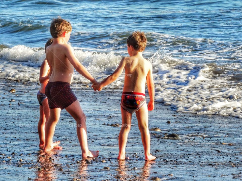 Three Brothers Holding Hands By The Sea. Kids Holding Hands