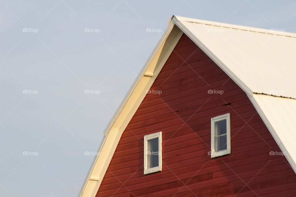 Isolated view of windows in the loft of a red barn against a clear sky