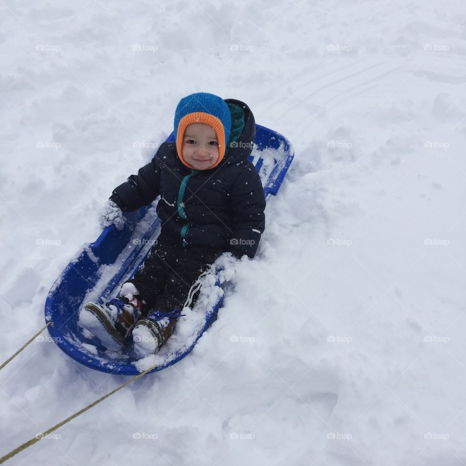 A little boy on sledge sliding on snow