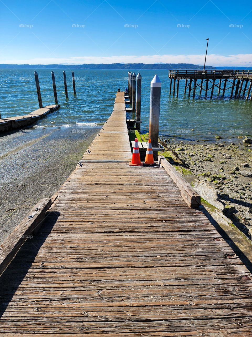A wooden pier and walkway jut into Puget Sound on a perfect summer day