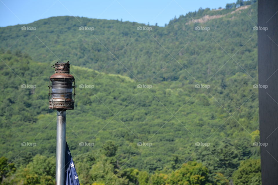 A boat light set in front of a forest backdrop with the American flag peeking out below