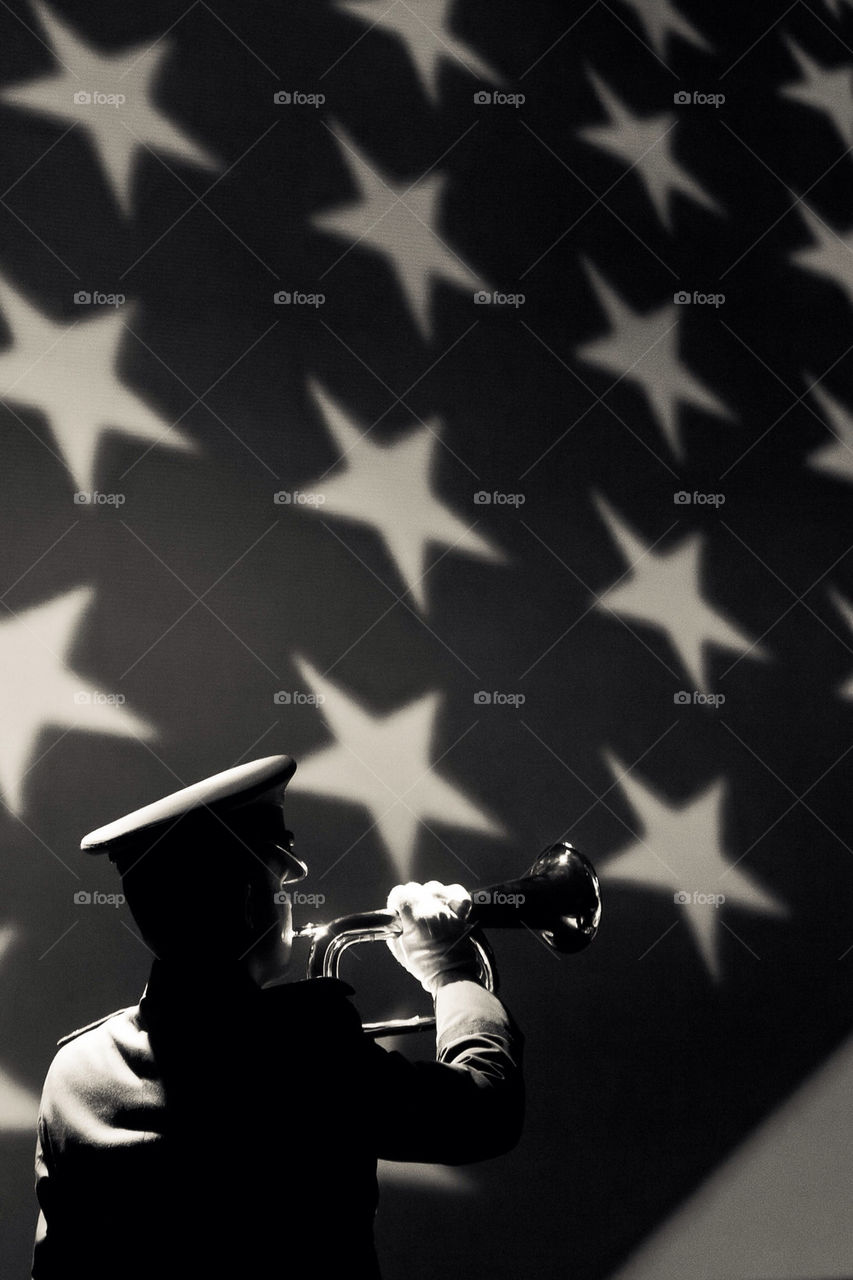 Silhouetted soldier playing in front of flag