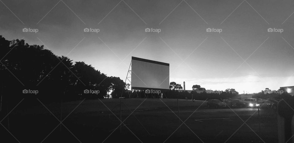 A drive-in theater or drive-in cinema is a form of cinema structure consisting of a large outdoor movie screen, a projection booth
