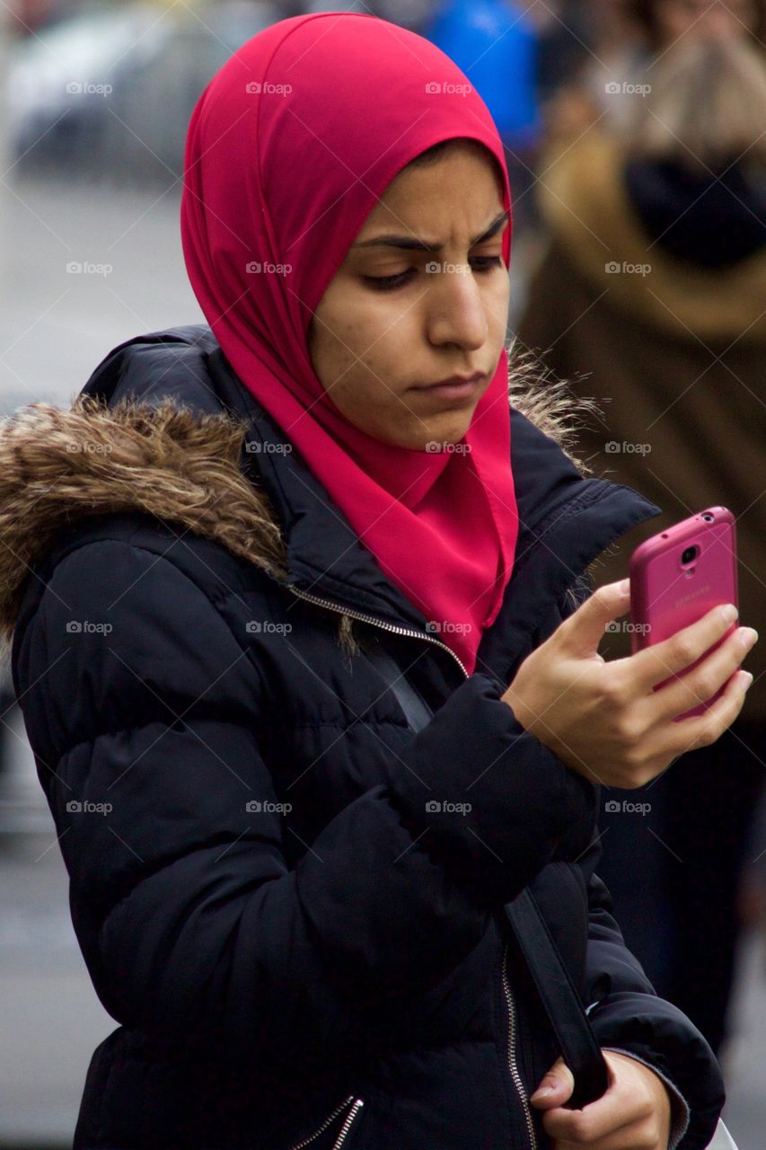 Young Muslim Woman Wearing Red Hijab Texting On Her Mobile Phone